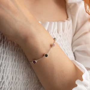 May include: A silver bracelet with a delicate chain and five colorful gemstones. The gemstones are round and set in silver.