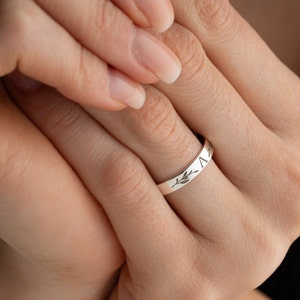 Könnte beinhalten: Ein silberner Ring mit einem zarten Blattdesign und der Inschrift "A" auf der Band.