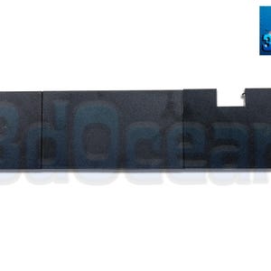 May include: A dark gray rectangular object with a cutout on one end. The object is divided into three sections and has the partially visible text "3dOcean" printed on it. The background is white.