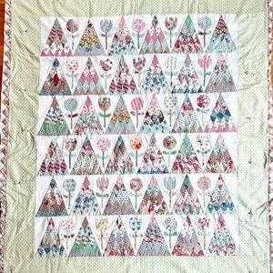 May include: A patchwork quilt with a white background and a pattern of green, pink, and brown triangles. Each triangle features a floral design and a small flower stem in the centre. The quilt is edged with a light green border.