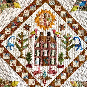 May include: A colorful quilt with a brown, pink, and green house in the center. The house is surrounded by trees, flowers, and animals. The quilt is made with a variety of fabrics and patterns.
