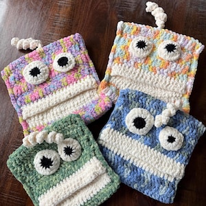 May include: Four crocheted monster-shaped zipper pouches in different colors and patterns. The pouches have white yarn for the mouth and black yarn for the eyes. The pouches are made with a variety of colorful yarns, including pink, purple, green, blue, and white.