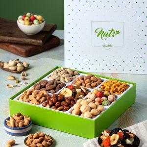 May include: A green box and tray filled with various nuts and dried fruits. The box has a white lid with green polka dots and the word "Nuts" in a script font. The tray contains almonds, cashews, pistachios, and other assorted nuts and dried fruits.