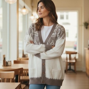 May include: A white and brown knit cardigan featuring a V-neckline, a button-down front with four brown buttons, and two front pockets. The garment displays a brown patterned design across the shoulders and along the bottom hem and cuffs.