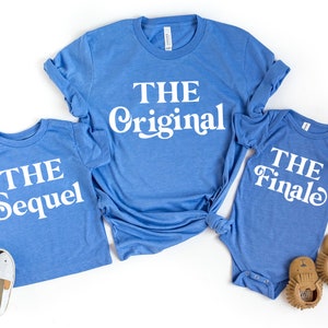 May include: Three blue t-shirts with white text. The largest shirt says "THE ORIGINAL". The medium shirt says "THE SEQUEL". The smallest shirt says "THE FINALE".