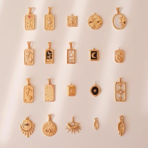 May include: A collection of gold-colored pendants with various celestial and floral designs. The pendants include suns, moons, stars, and other symbolic shapes. Some pendants have intricate details, while others are more minimalist.