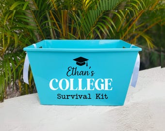 May include: A bright turquoise plastic storage bin with white side handles. The front features a black graduation cap icon above the text "Ethan's COLLEGE Survival Kit" in a combination of black script, white block, and black typewriter fonts.