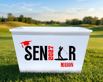 May include: A white plastic bin featuring a red graduation cap icon above the black text SENIOR, with the number 2027 in red replacing the letter I. A black silhouette of a golfer is integrated into the letter R, and the name MASON is in red.
