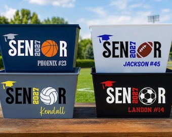 May include: Four rectangular plastic storage bins in navy, white, gray, and black. Each bin features the text SENIOR 2027 with a graduation cap icon and a sports ball replacing the letter O. Names and numbers are printed below the main text.