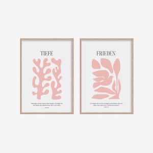 May include: Two framed prints with pink abstract floral designs and inspirational quotes in German. The left print says "Tiefe" and the right print says "Frieden".