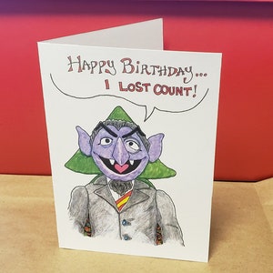 May include: A humorous birthday card featuring a cartoon illustration of Count von Count from Sesame Street. The card reads "Happy Birthday... I Lost Count!"