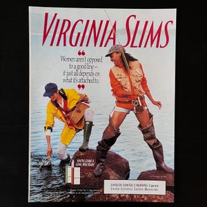 Peut inclure: Une publicité vintage pour des cigarettes Virginia Slims mettant en scène deux femmes à la pêche. Le texte dit "Les femmes ne sont pas opposées à une bonne ligne - tout dépend de ce à quoi elle est attachée." et "Vous avez fait du chemin, bébé". La publicité comprend un avertissement du chirurgien général : la cigarette contient du monoxyde de carbone.