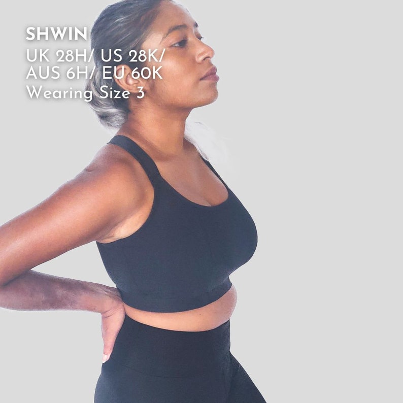 Op de afbeelding: Een zwarte sportbeha met racerback-ontwerp. Het model draagt maat 3. De tekst op de afbeelding luidt: "SHWIN UK 28H/US 28K/AUS 6H/EU 60K Wearing Size 3"
