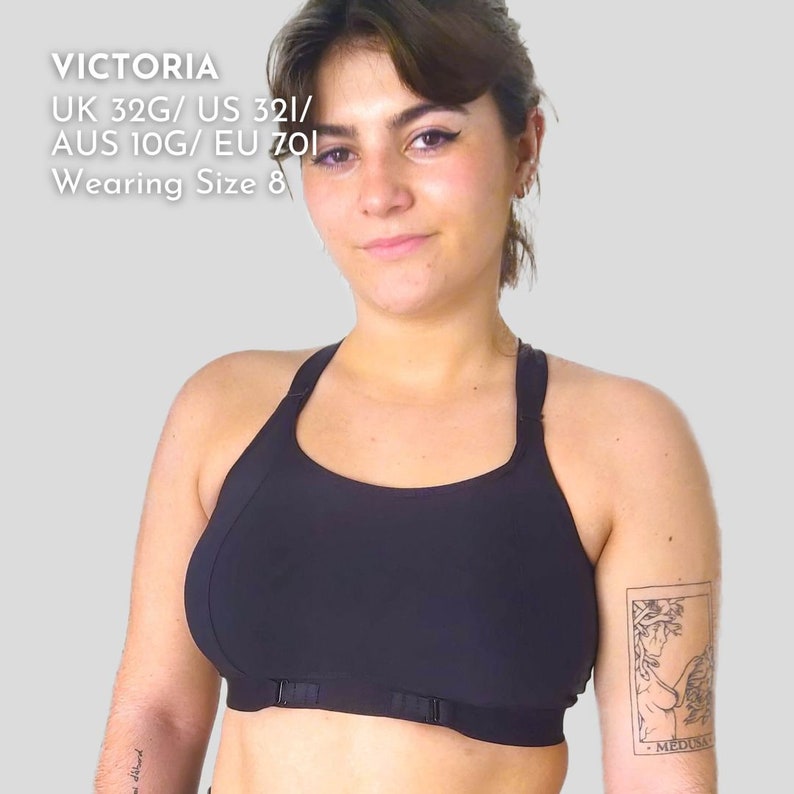 Op de afbeelding: Een zwarte sportbeha met verstelbare bandjes en een haak- en oogsluiting. De beha wordt gedragen door een persoon met een tatoeage op hun arm die "MEDUSA" zegt. De tekst op de afbeelding luidt "VICTORIA UK 32G/US 32I/AUS 10G/EU 70I Wearing Size 8"