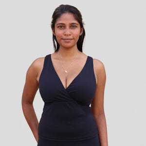 May include: A black sleeveless top with a deep V-neckline and a wrap-style design. The top is made of a soft, stretchy fabric and has a relaxed fit.