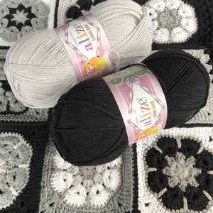 May include: Two balls of yarn, one grey and one black, with the Alize brand label. The yarn is cotton and is for crocheting.