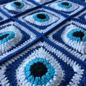 May include: Crocheted blanket with a blue and white pattern featuring multiple evil eye designs.