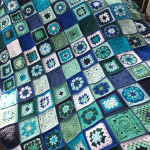 May include: A crocheted blanket with a square pattern in shades of blue, green, and white.