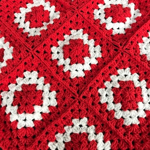 Op de afbeelding: Rood en wit gehaakt deken met een vierkant patroon.