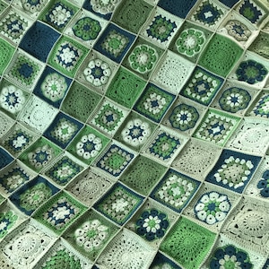Könnte beinhalten: Eine gehäkelte Decke mit verschiedenen grünen, blauen und weißen Quadraten. Die Decke ist mit einem Granny-Square-Muster gearbeitet.