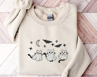May include: A cream-colored sweatshirt with a black graphic of three cats dressed as ghosts with bats and stars in the background.