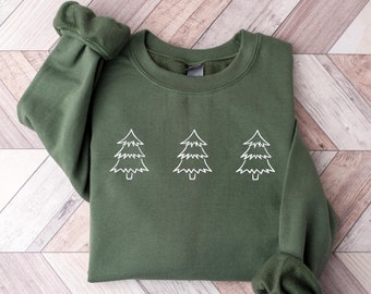 Può includere: Una felpa verde con tre alberi di Natale bianchi in contorno sul davanti.