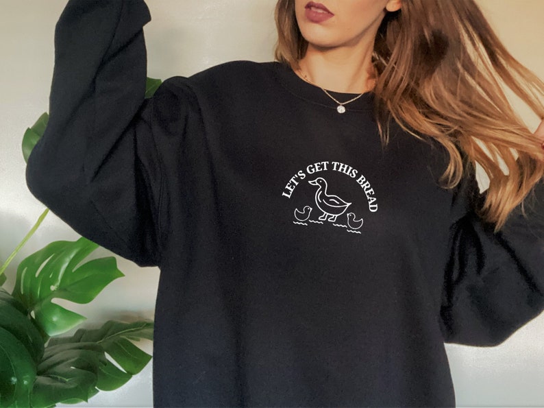 May include: Black sweatshirt with a white embroidered design of a duck and ducklings with the text "Let's get this bread".