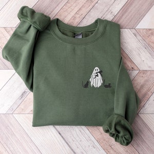 May include: A green sweatshirt with a white ghost holding a cat and two black cats on the front.