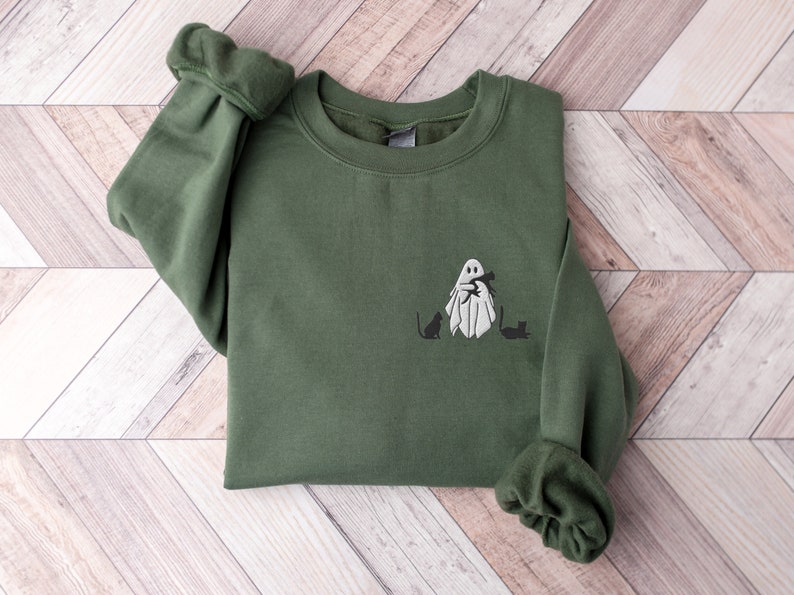 May include: A green sweatshirt with a white ghost holding a cat and two black cats on the front.