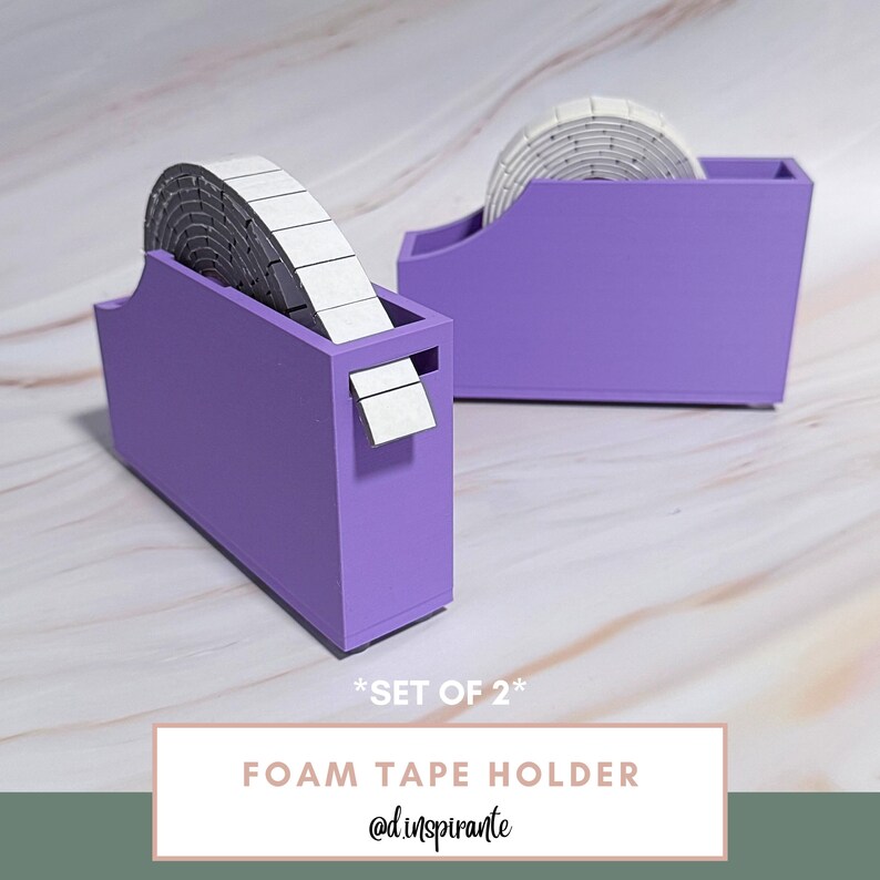 May include: Two purple foam tape holders with rolls of white and gray foam tape. The holders have a rectangular shape with a slot for dispensing the tape. The text "FOAM TAPE HOLDER" and "@d.inspirante" are visible.