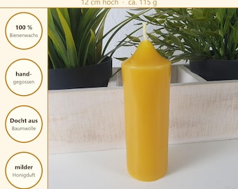 May include: A yellow beeswax pillar candle with a cotton wick. The text on the image reads Bienenwachskerze, 12 cm hoch, ca. 115 g, 100% Bienenwachs, hand-gegossen, Docht aus Baumwolle, milder Honigduft, Aus eigener Werkstatt, Made in Germany.