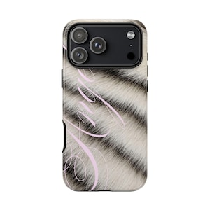 Può includere: Una custodia per telefono con un motivo a strisce bianche e nere, simile alla pelliccia di tigre. La custodia ha un modulo fotocamera nero con tre obiettivi e una sovrapposizione di testo rosa in corsivo che dice "Ange".