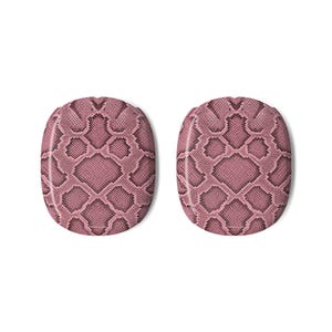 May include: Two oval-shaped headphone ear cushion covers featuring a pink and black snakeskin pattern. The covers have a rounded rectangular silhouette with a textured surface design that mimics the appearance of reptile scales in shades of pink.