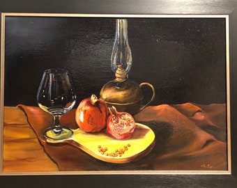 Könnte beinhalten: Ein Stillleben mit einem Glas, zwei Granatapfelhälften und einer Öllampe auf einem Holztisch mit einem braunen Tuch. Das Gemälde ist in Schwarz gerahmt.