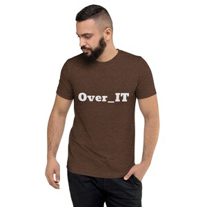 Pode incluir: Camiseta marrom de manga curta com o texto "Over_IT" impresso em branco na frente.