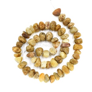 May include: A strand of natural stone beads in shades of brown, beige, and white. The beads are irregularly shaped and have a rough, tumbled texture.