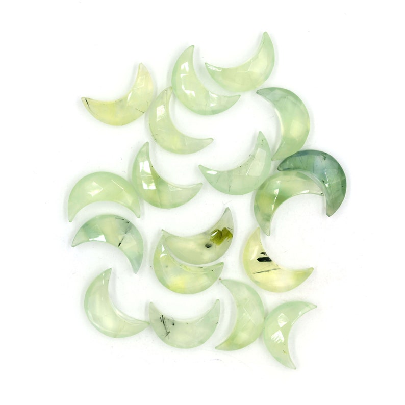 May include: A collection of green and white crescent moon shaped crystals. The crystals are polished and have a translucent appearance.