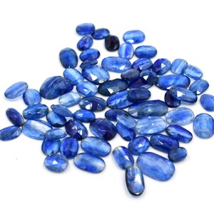 May include: A collection of blue kyanite gemstones, each with a unique, faceted oval shape. The stones have a light blue color with a slight shimmer.