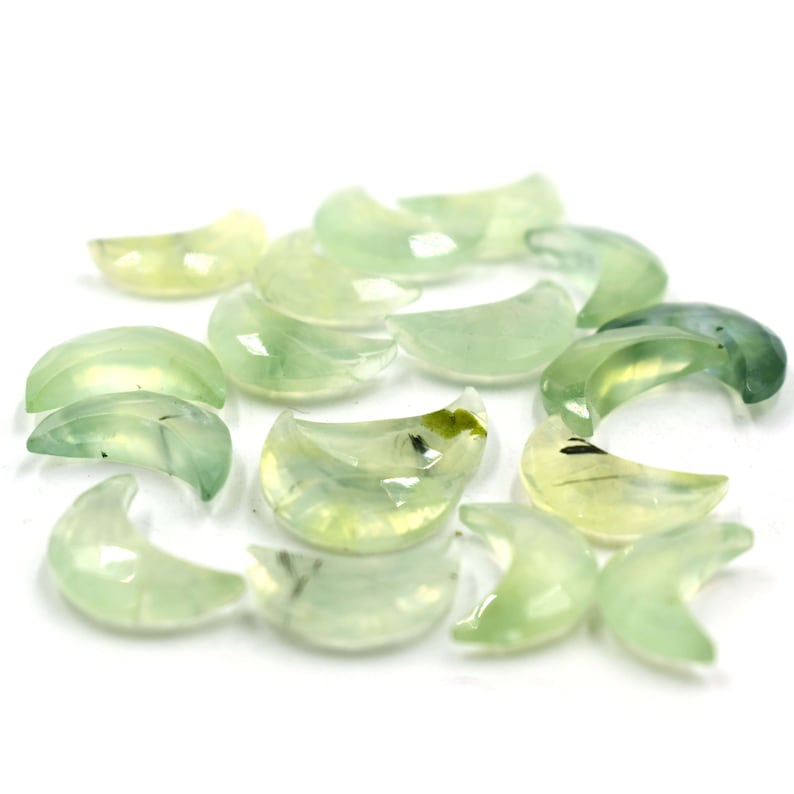 May include: A collection of green and white crescent moon shaped crystals. The crystals are smooth and polished.