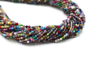 May include: A strand of colorful gemstone beads, featuring a variety of colors and shapes. The beads are small and round, and they are strung together on a clear thread. The beads are a mix of opaque and translucent, and they have a natural, unpolished finish.