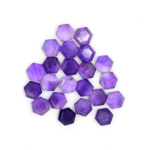 May include: A collection of 18 purple amethyst gemstone cabochons, each cut into a hexagonal shape. The stones are arranged in a loose, overlapping pattern.