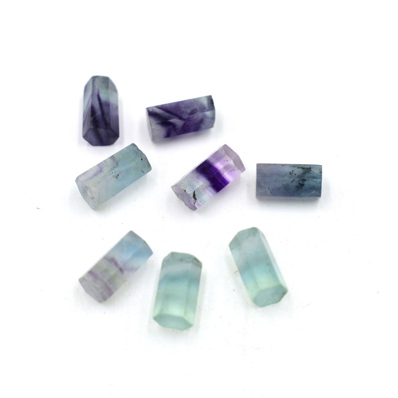 Puede incluir: Ocho cuentas de fluorita facetadas en varios tonos de azul y morado. Las cuentas son de forma rectangular y tienen un acabado liso y pulido.