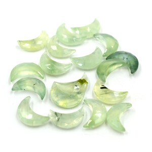 May include: A collection of green and white crescent moon shaped crystals. The crystals are translucent and have a natural, organic look.