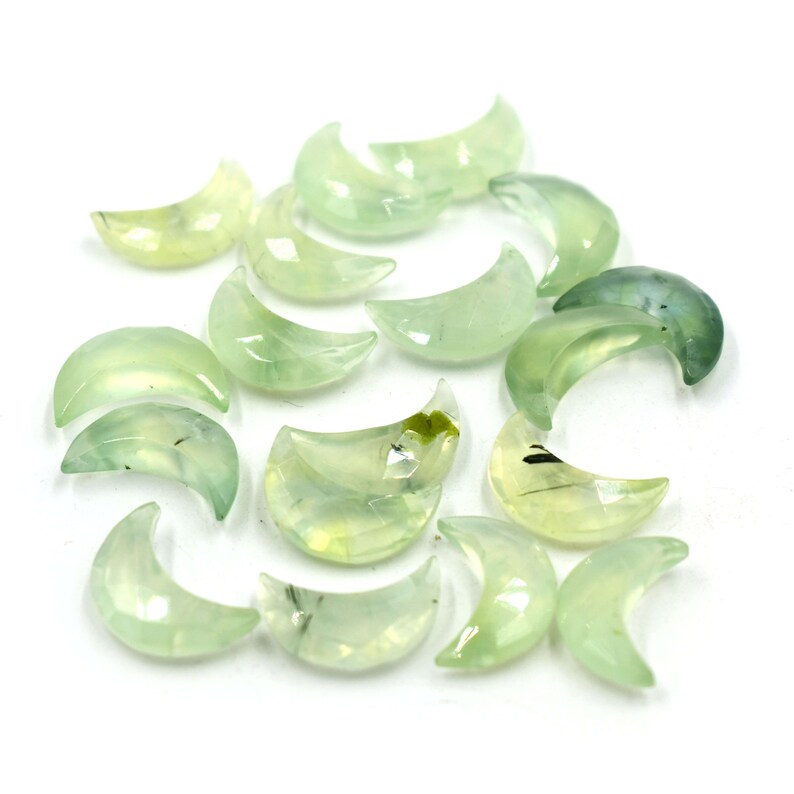 May include: A collection of green and white crescent moon shaped crystals. The crystals are translucent and have a natural, organic look.