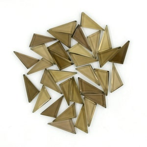 Puede incluir: Una colección de pequeñas baldosas de vidrio triangulares en tonos marrones. Las baldosas están dispuestas en un círculo suelto sobre un fondo blanco.