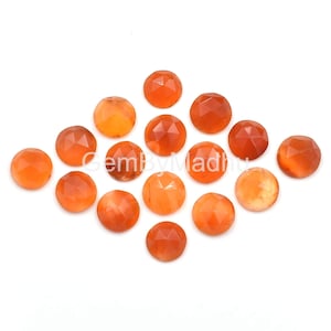 May include: A collection of 15 orange carnelian gemstone cabochons, each with a faceted, rounded shape. The stones are arranged in a diamond pattern on a white background.