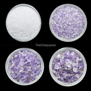 May include: Four glass bowls filled with amethyst crystals. The bowls are arranged in a square pattern on a black background. The crystals are a light purple color and are of various sizes.