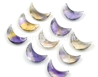 May include: A collection of faceted gemstone crescent moons in shades of purple, yellow, and clear. The gemstones are arranged on a white surface, showcasing their polished surfaces and unique color gradients. The overall theme is celestial and decorative.