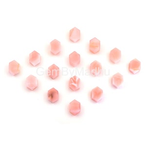 Puede incluir: Una colección de 16 piedras preciosas hexagonales de color rosa. Las piedras preciosas están dispuestas en forma de diamante sobre un fondo blanco.