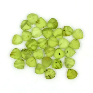 May include: A collection of 25 light green, triangular shaped gemstones with a slightly translucent appearance. The gemstones have a natural, organic look with subtle variations in color and texture.
